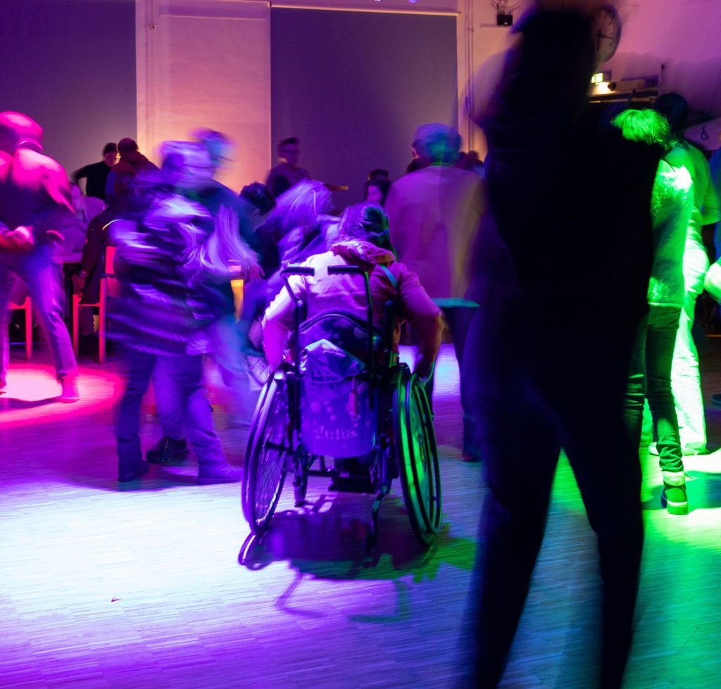 Tanzender Rollstuhlfahrer in bleuem Licht bei einer Party