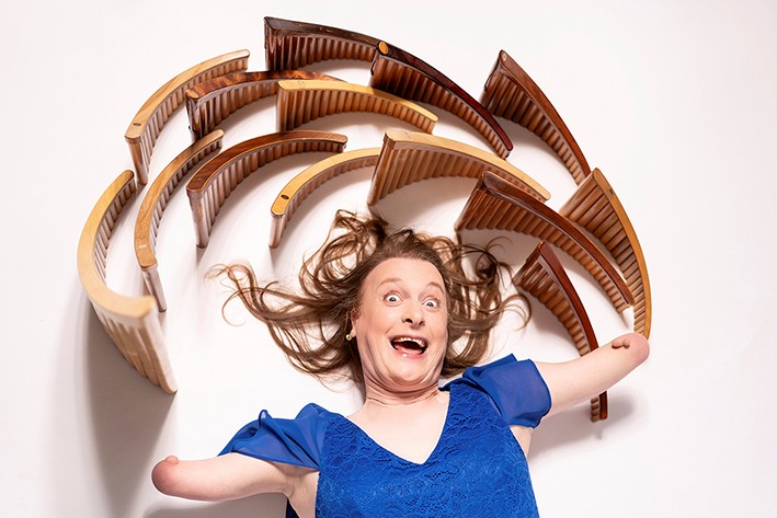 Eine Frau liegt auf einem weißen Boden, um ihren Kopf herum sind Panflöten aufgestellt