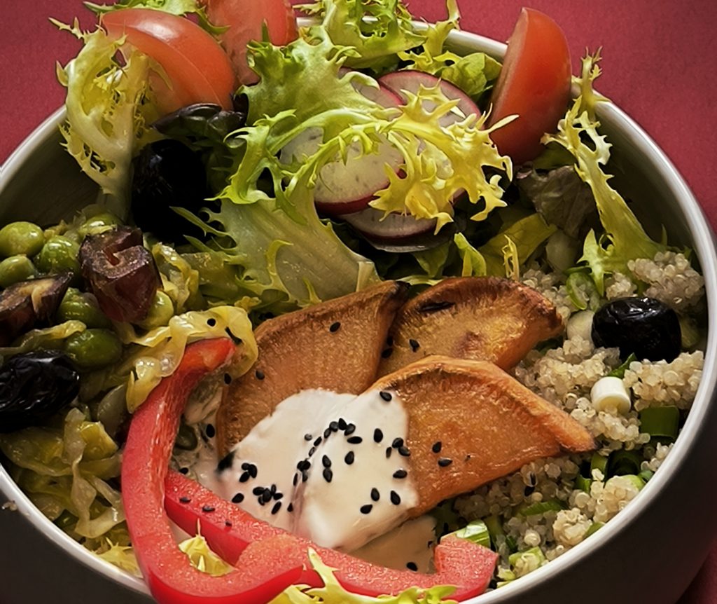 In einer Schale liegen Salat, Gemüse und Sauce lecker angerichtet