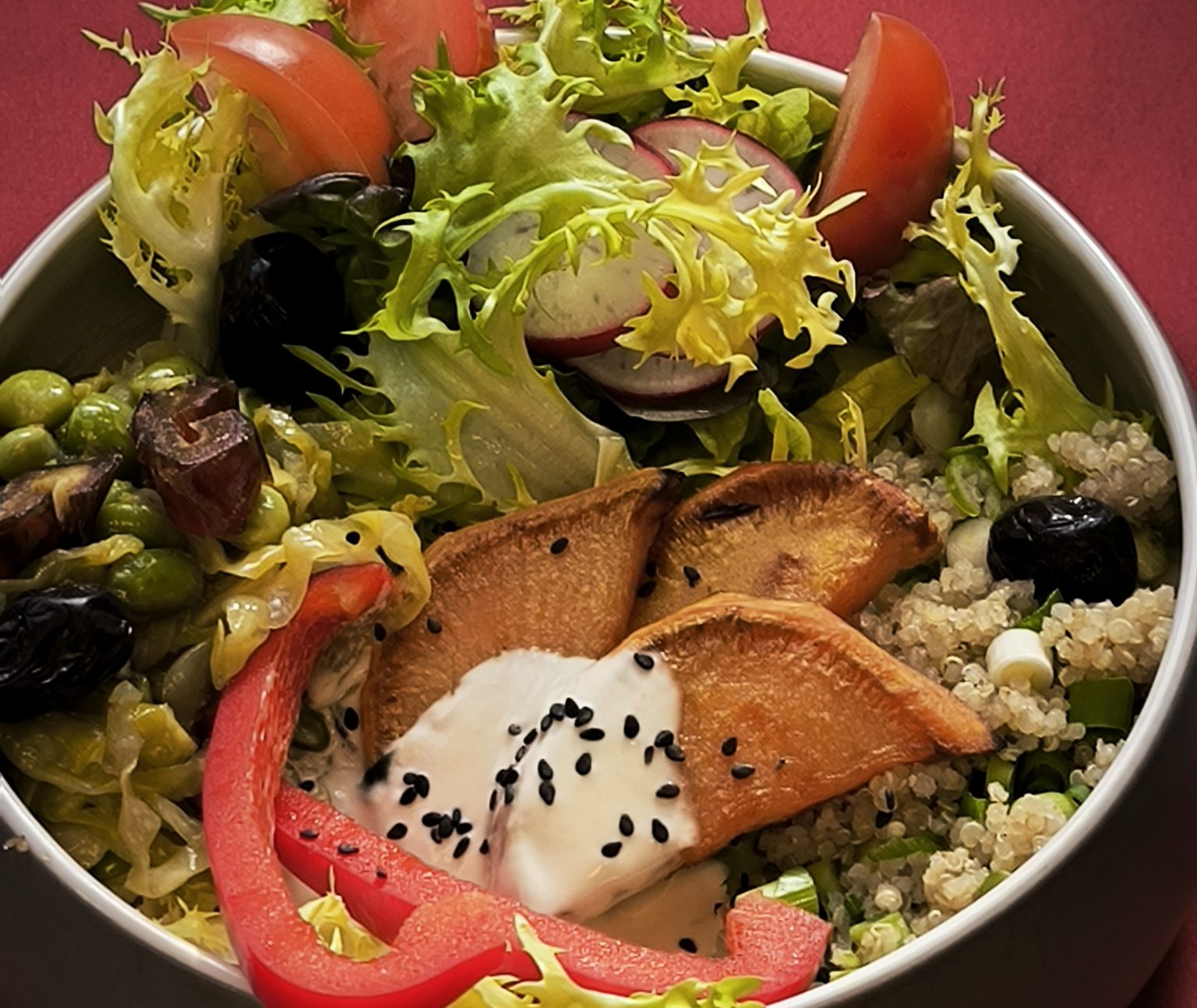 In einer Schale liegen Salat, Gemüse und Sauce lecker angerichtet