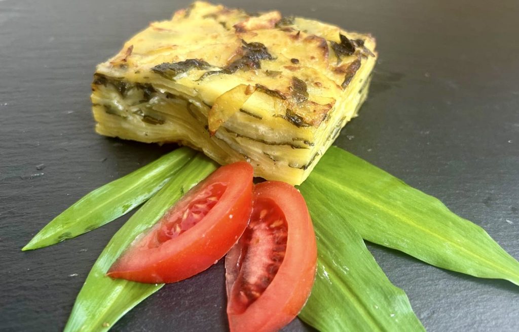 Auf ein paar Bärlauchblättern liegt ein quadratisches Stück Auflauf