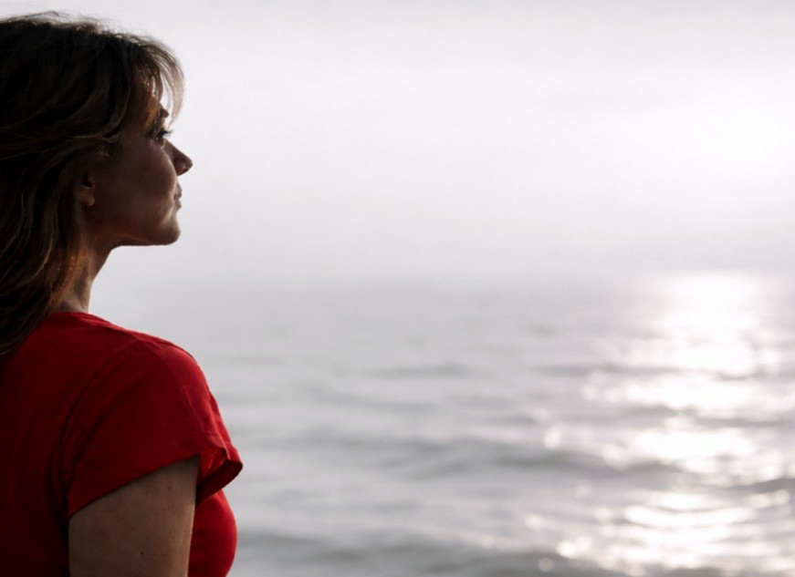 Frau guckt im Abendlich auf das Meer